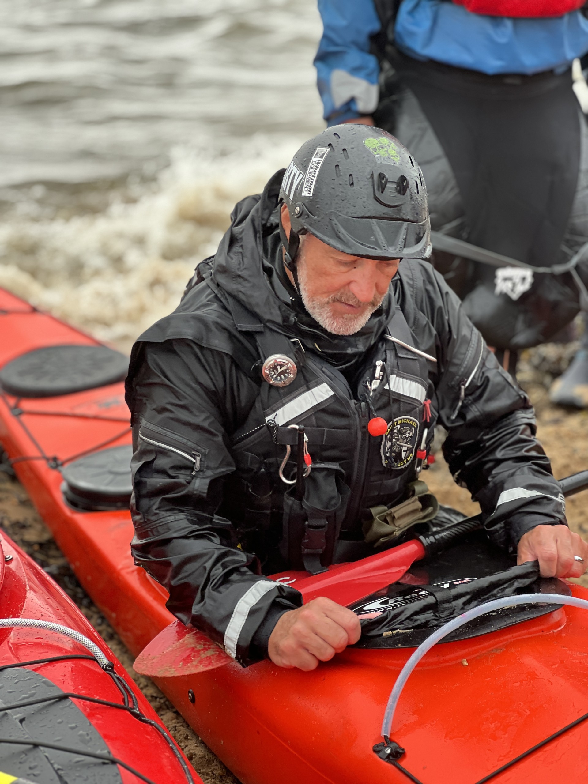 Putting on a spraydeck; bank coaching with NOMAD Sea Kayaking.