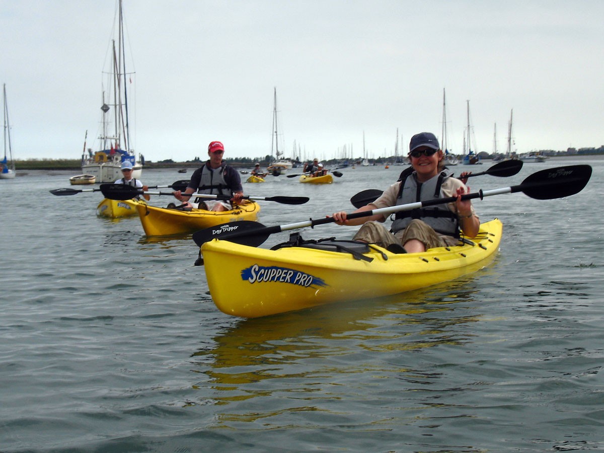 Kayakers on sit-on-tops with yachts in the background