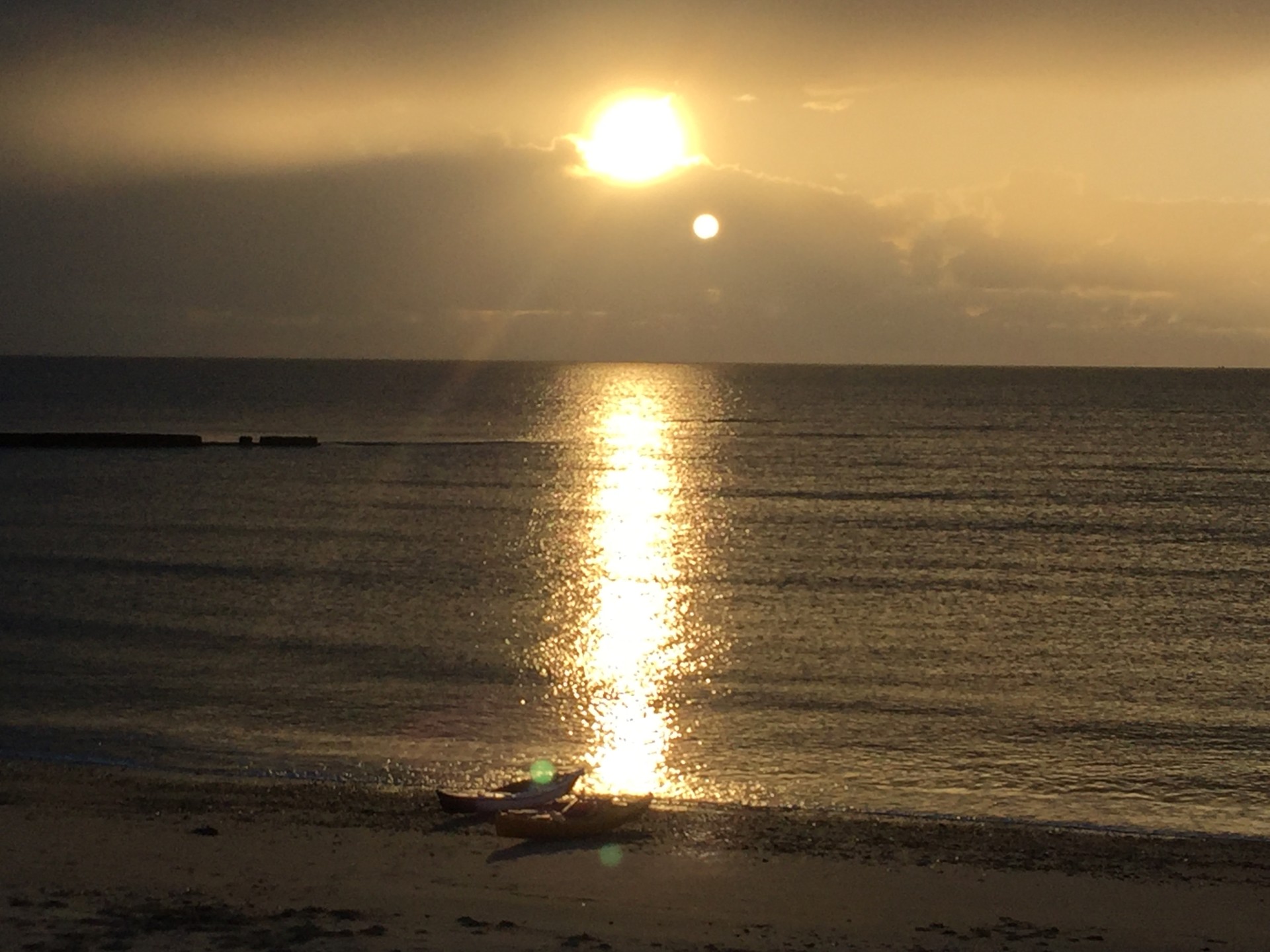 Sea kayaks on a sandy beach at sunset in Essex with NOMAD Sea Kayaking.