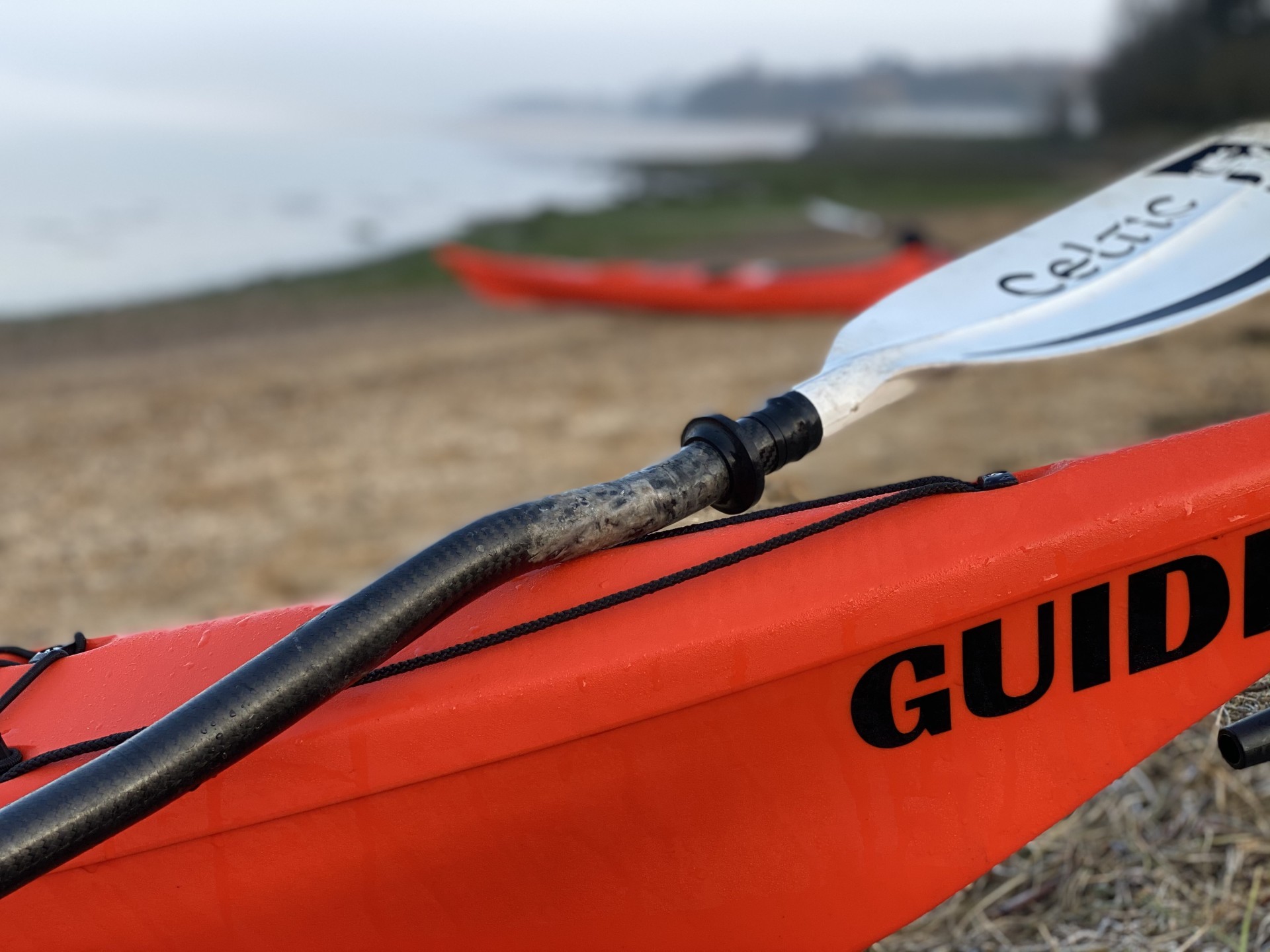 Bow of an orange sea kayak on a beach.