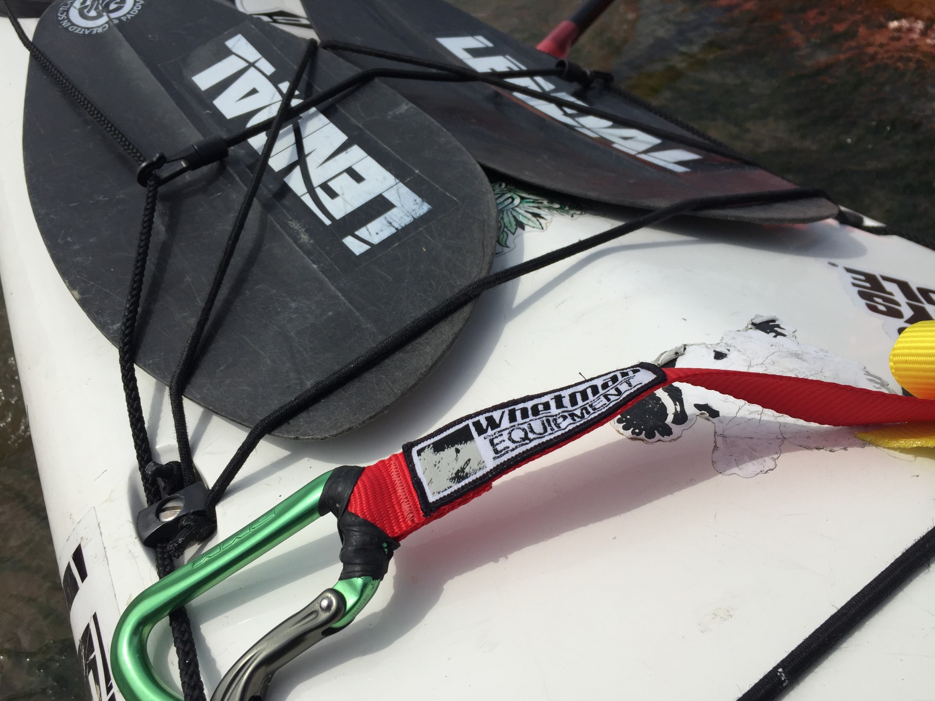 A black split paddle attached to the front deck of a sea kayak on the Intermediate Sea Kayaking training course.