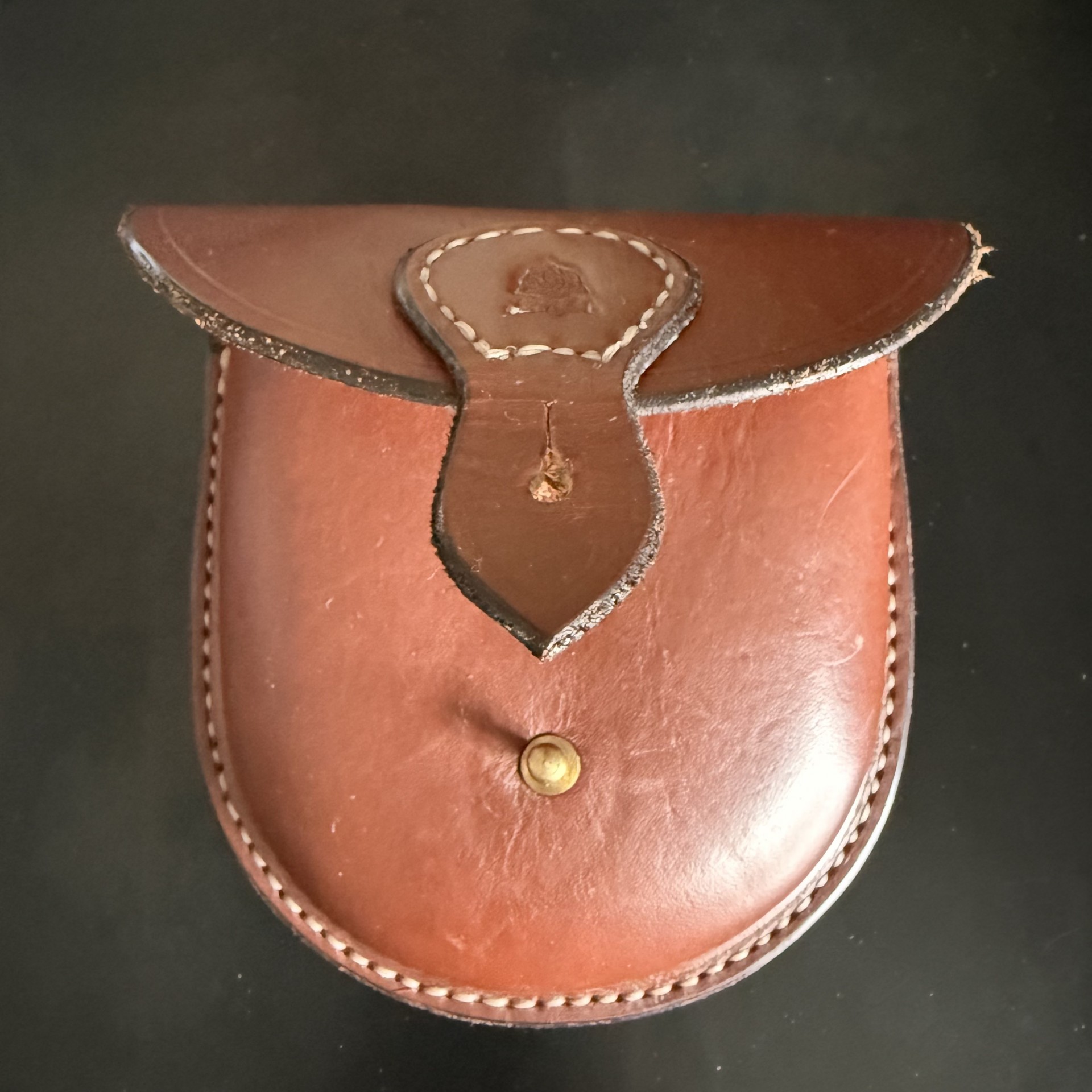 Brass button press on leather belt pouch.