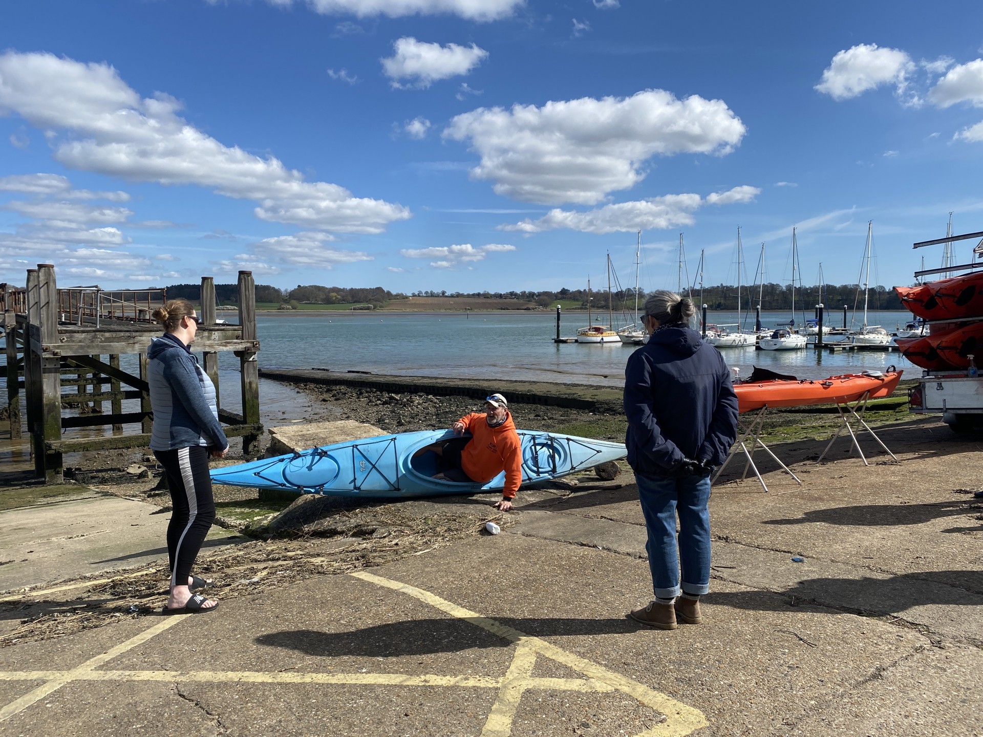 Coach sitting in a touring kayak and demonstrating the concept of 'edging'.