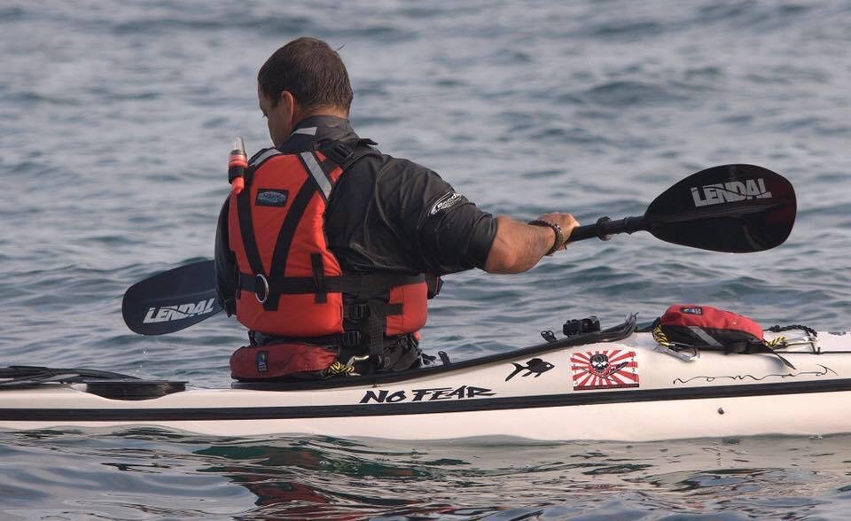 Sea kayaker sitting in a white sea kayak with stickers.