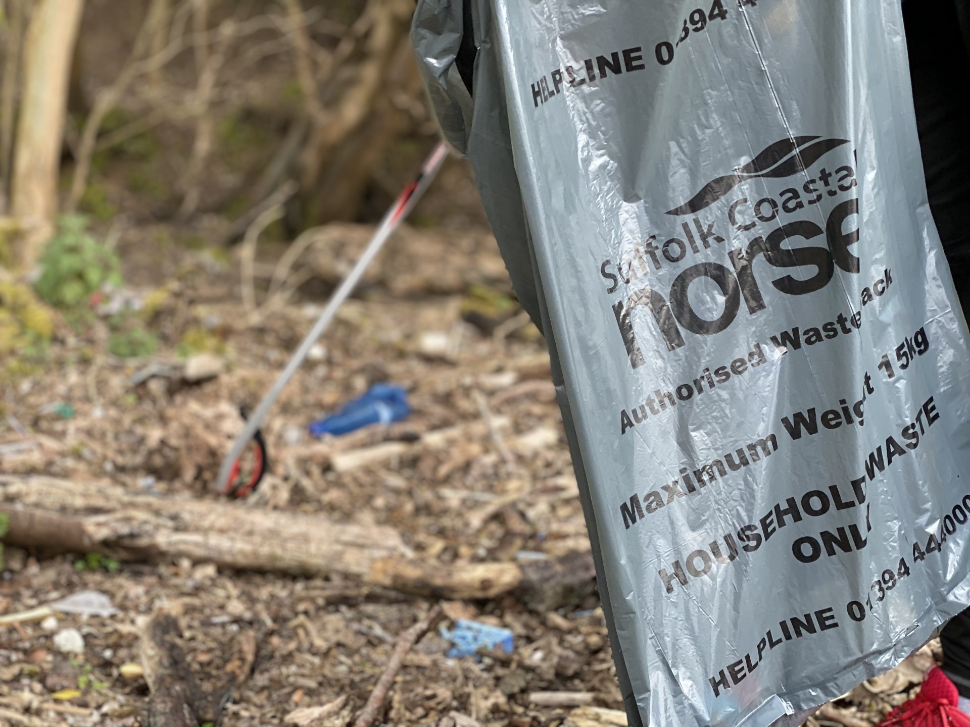 Volunteers using litter pickers to collect jetsam trash on a Suffolk beach.