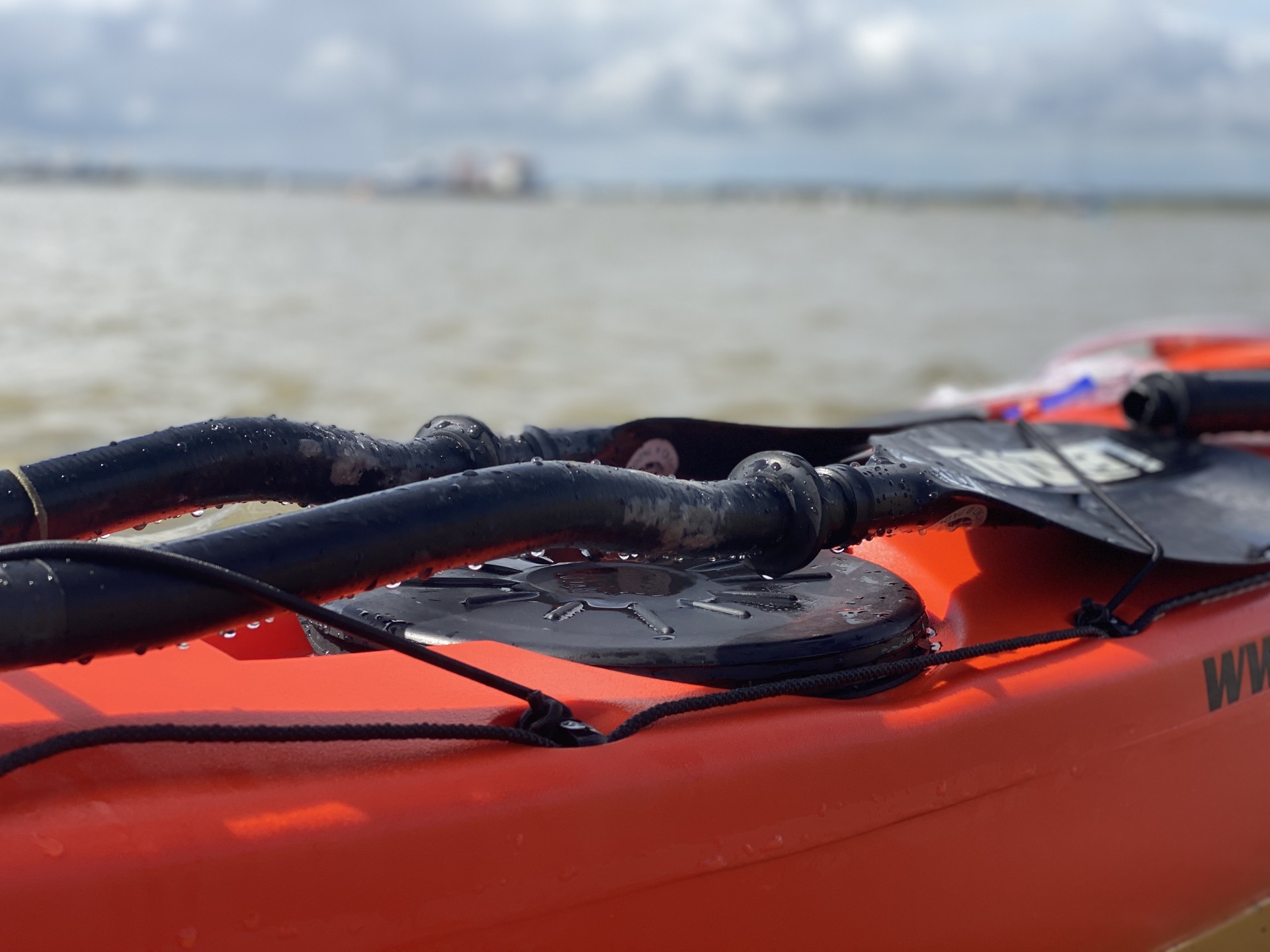 Split paddles on the front deck of an orange sea kayak with NOMAD Sea Kayaking.