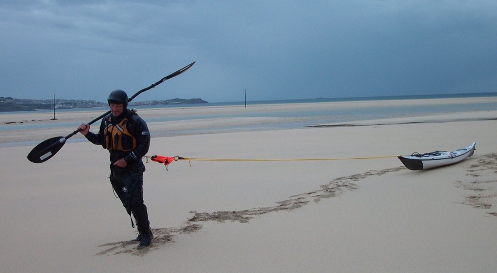 Dragging a sea kayak up a very long sandy beach.